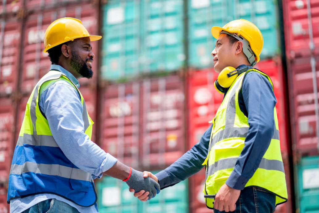 African American worker or technician shake hands with Asian staff in cargo container workplace