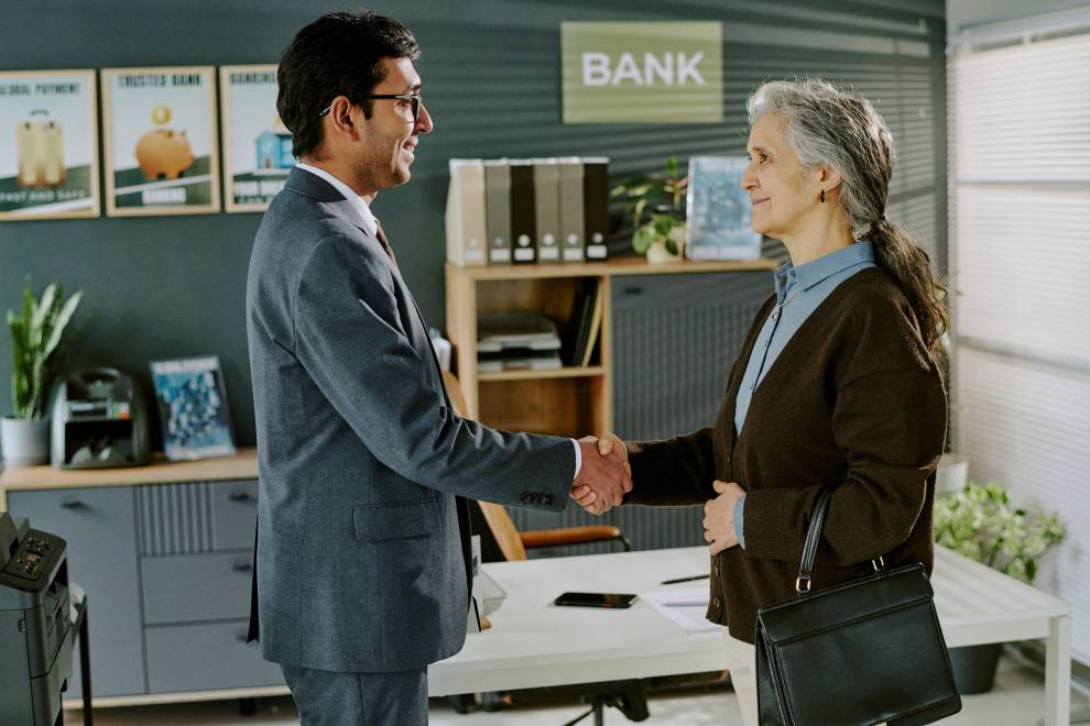 Businessman Shaking Hands with Elderly Hispanic Woman in Office