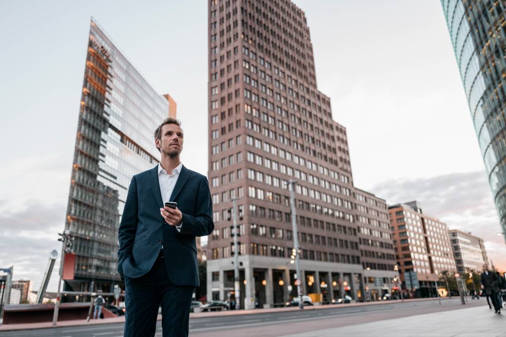 Germany, Berlin, businessman with smartphone standing at Potsdamer Platz