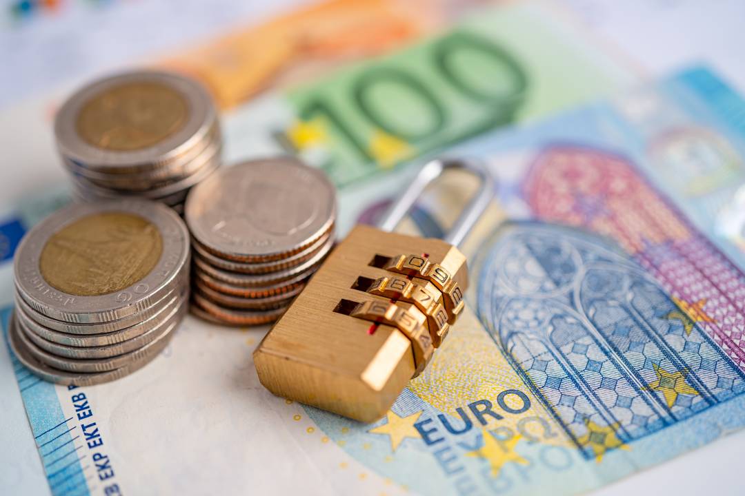 Golden security digital password lock key and coins with with Euro banknotes on graph