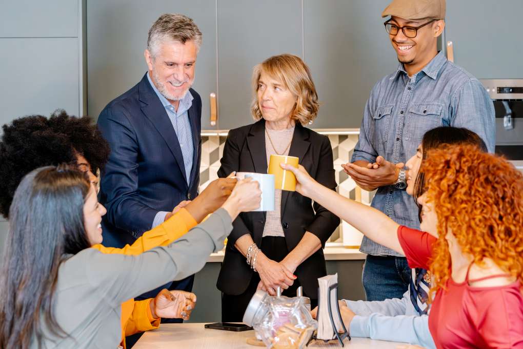 Group of colleagues sharing coffee break in a modern office kitchen.