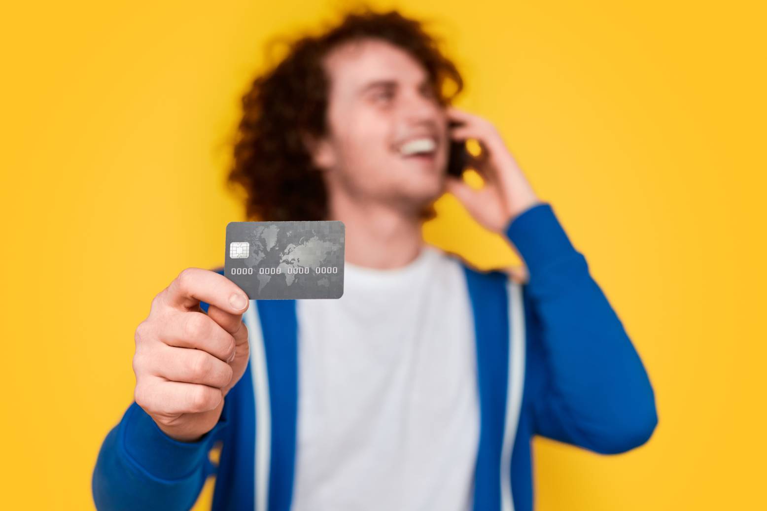 Man talking on phone and showing credit card