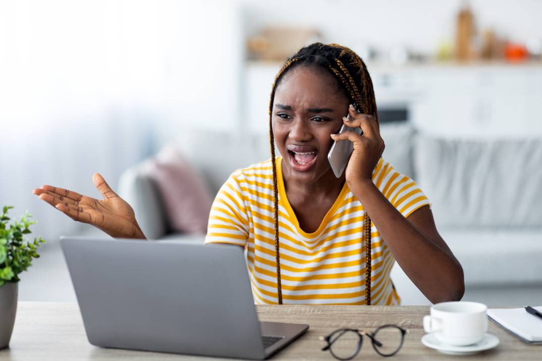 Nervous black woman working from home, fighting on phone