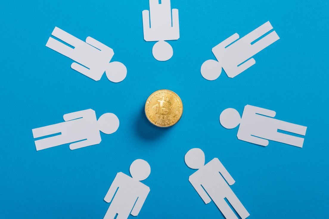Top view of white paper cut people in circle near golden bitcoin on blue