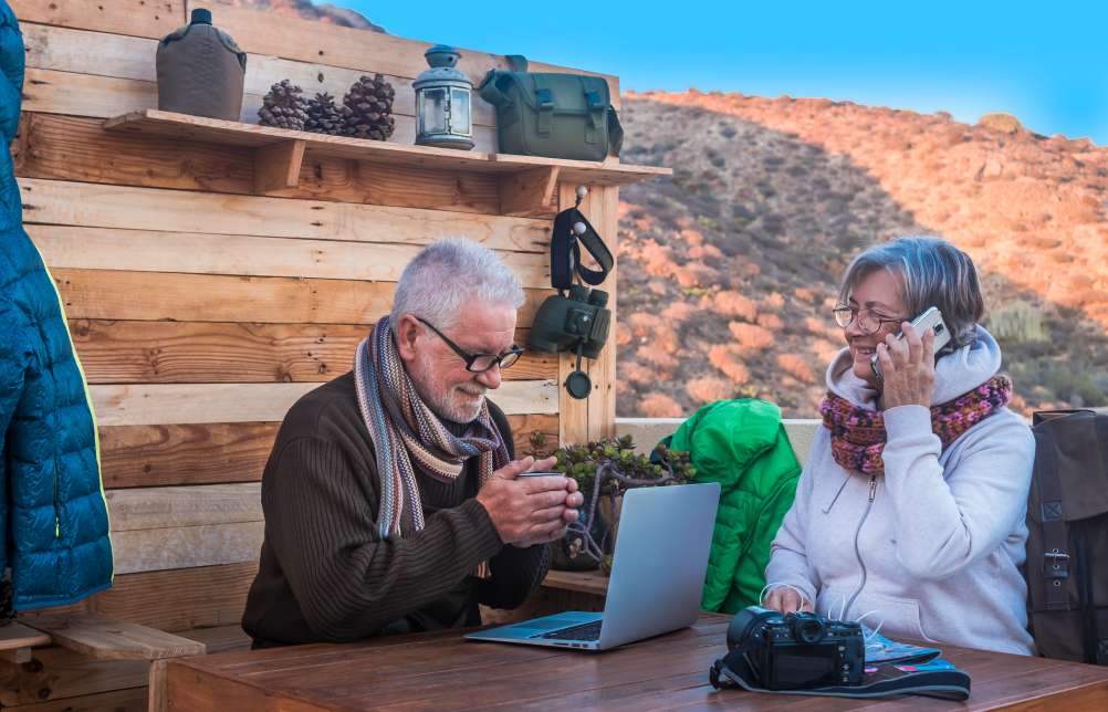 Two senior people enjoying a break after a walk at rustic mountain bar using technology