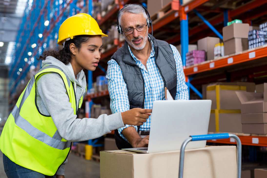 Warehouse manager and female worker using laptop
