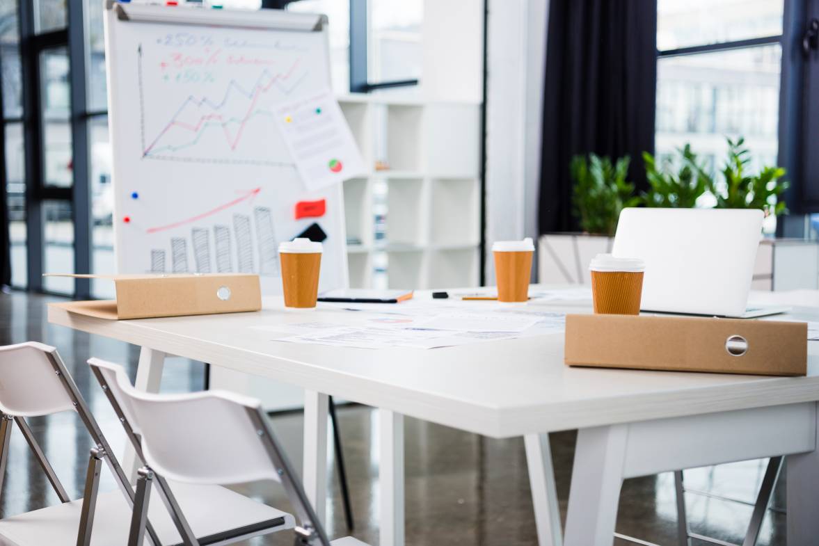 Workplace with laptop, coffee paper cups in modern office